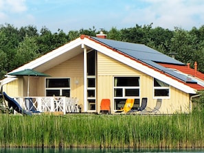 Ein Haus mit geneigtem Dach, großen Fenstern und einem Steg, der ins Wasser führt.