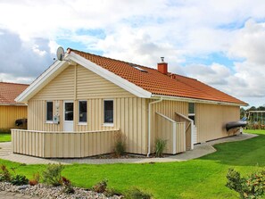 Ein eingeschossiges Haus mit rotem Ziegeldach, einer kleinen Veranda und einem Schornstein.