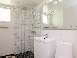 Een moderne badkamer met een douche, een wastafel en een spiegel.