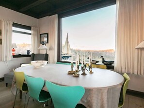 A dining area with a round table, chairs, a candelabra, and a view of the outdoors.