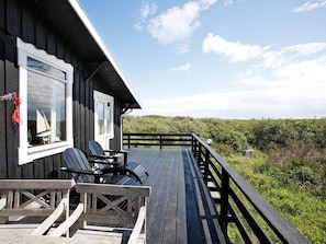 A wooden deck with two chairs and a table, overlooking a lush landscape.
