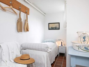 A bedroom with a bed, a nightstand, a lamp, a hat, and a wall-mounted shelf with a decorative item. - Peaceful Holiday Home in Skagen near Sea (Skagen)