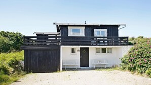 A two-story building with a flat roof, a front door, and a small porch with benches. - Peaceful Holiday Home in Skagen near Sea (Skagen)