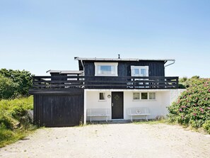 A two-story building with a flat roof, a front door, and a small porch with benches. - Peaceful Holiday Home in Skagen near Sea (Skagen)