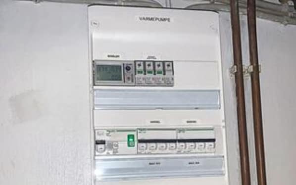 A white electrical panel with multiple switches and indicators, labeled 'VARME PUMPE.'