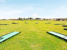 Un campo cubierto de hierba con varios bancos verdes dispuestos en semicírculo.