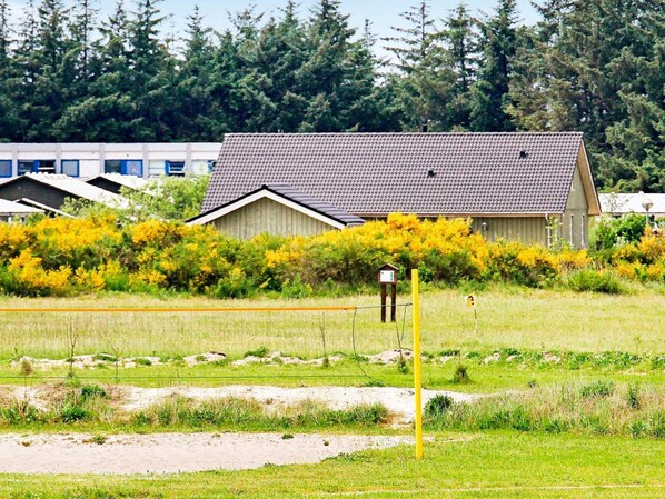 A rural setting with a large house, a fenced field, and a row of smaller buildings in the background.