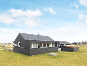 A modern two-story house with a dark exterior, large windows, and a flat roof.