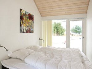 A bedroom with a bed, a painting, and a window with curtains. - 4 Star Holiday Home in Brovst (Brovst)