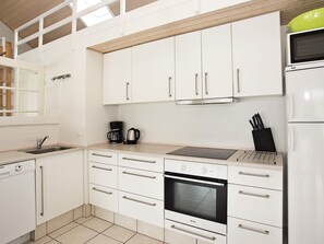 A kitchen with white cabinets, a built-in oven, a microwave, and a coffee maker. - 4 Star Holiday Home in Brovst (Brovst)