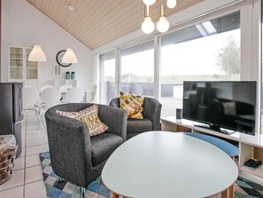 A modern living room with a grey sofa, a round table, and a flat-screen TV. - 4 Star Holiday Home in Brovst (Brovst)