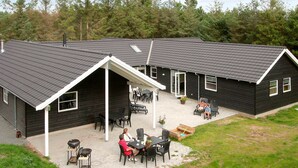 Een zwart gebouw met een schuin dak en een overdekt terras met buitenmeubilair.