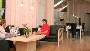 Een modern interieur met een houten wand, een eethoek met een tafel en stoelen, en een zithoek met een bank en salontafel.