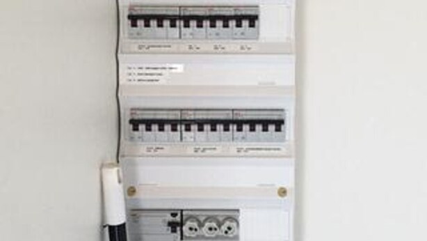 Ein an der Wand montierter Stromverteiler mit mehreren Schutzschaltern und einem Schalter.