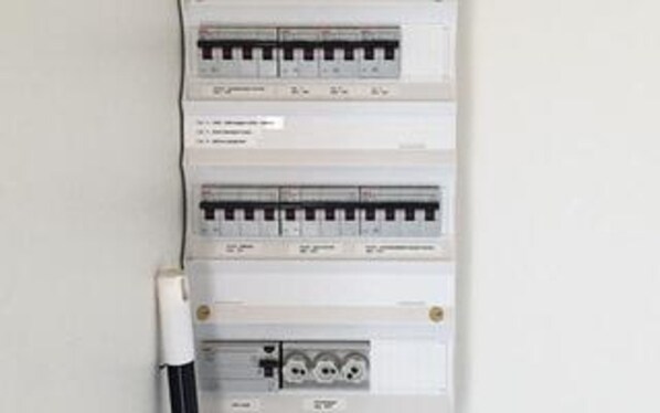 A wall-mounted electrical panel with multiple circuit breakers and a switch.