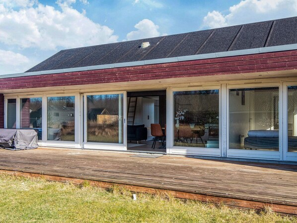 Une maison moderne dotée d’une grande terrasse, de portes-fenêtres coulissantes et d’un espace extérieur abrité.