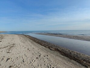 Una playa con cielo despejado, orilla arenosa y agua tranquila.