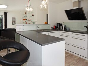 A modern kitchen with a central island, white cabinetry, and a black countertop.