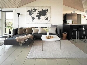 Ein modernes Wohnzimmer mit einer Eckcouch, einem Couchtisch und einer Weltkarte an der Wand.