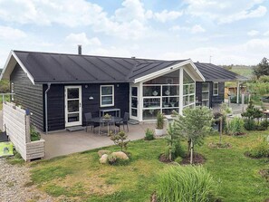 A modern house with a large patio area, a covered outdoor seating area, and a well-maintained garden. - 5 Star Holiday Home in Lokken (Lokken)