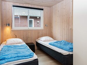 A room with two beds, wooden walls, a window with a view, and a wall-mounted light fixture. - 5 Star Holiday Home in Nordborg (Nordborg)
