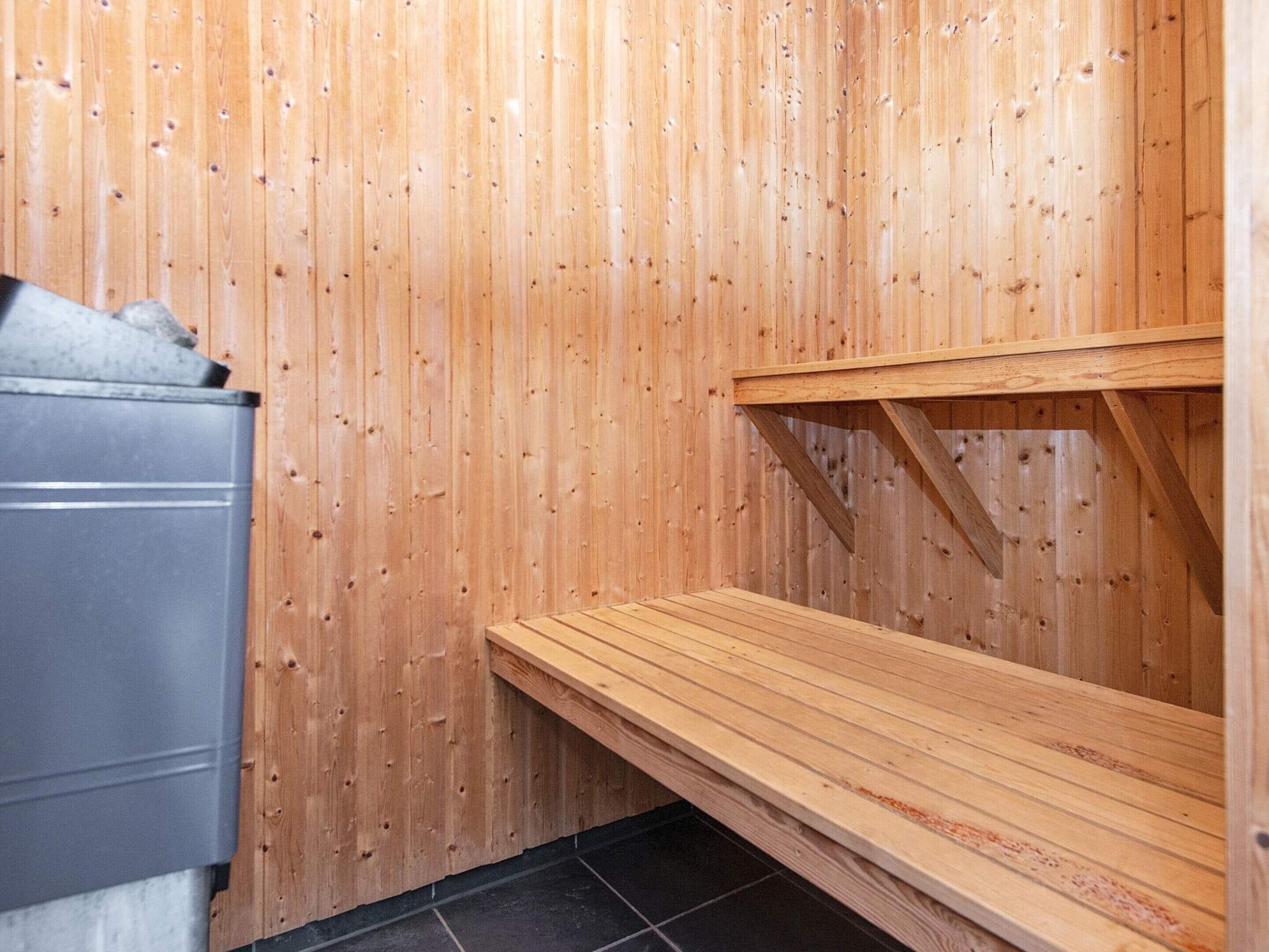 A sauna room with wooden walls and a bench.