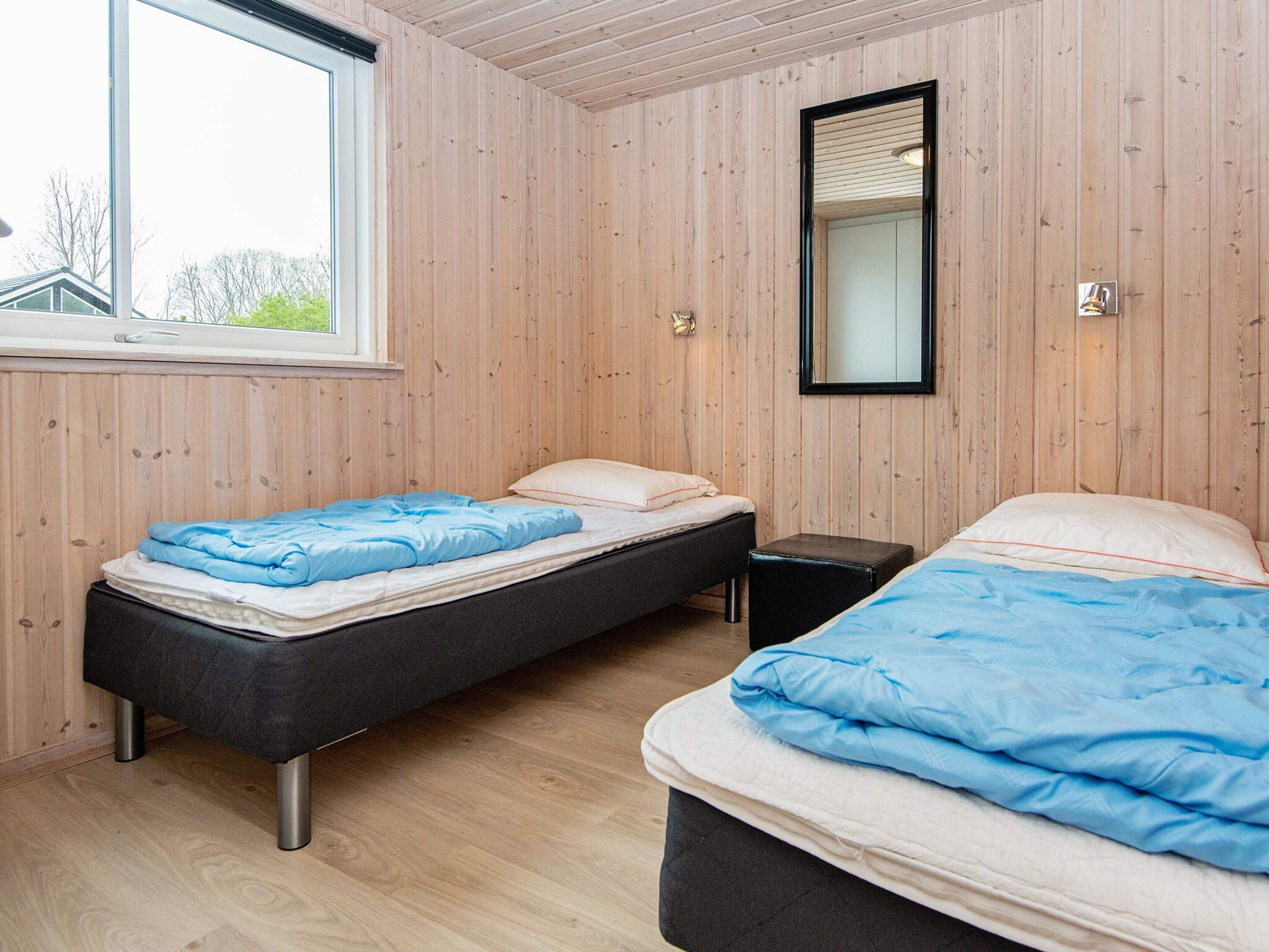 A room with two beds, a window, and a mirror.