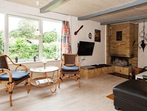 Ein gemütliches Wohnzimmer mit Kamin, Korbmöbeln und einem Fernseher.