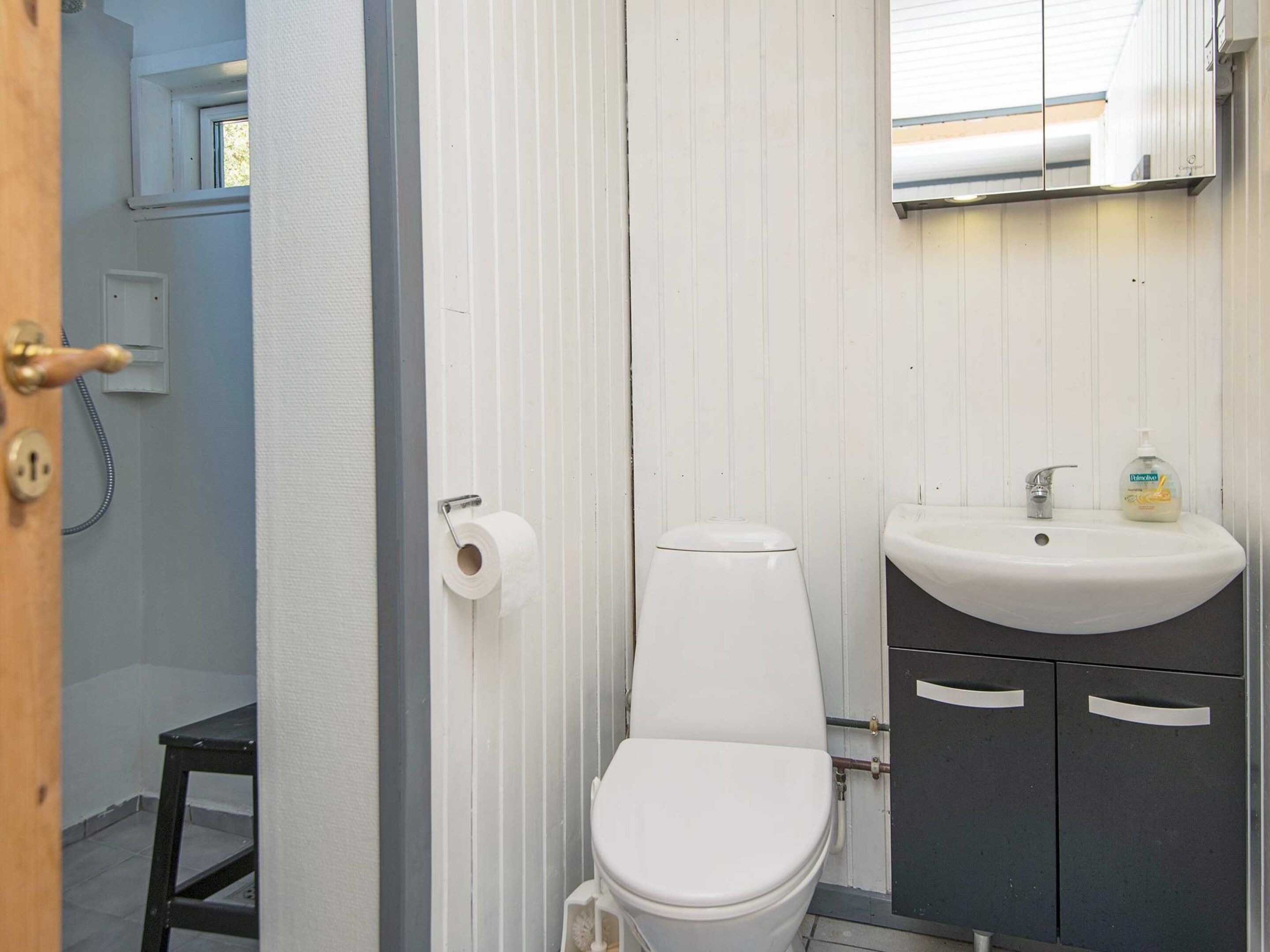 A compact bathroom with a toilet, a sink, and a small window.