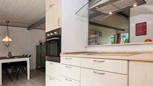 A kitchen with a large oven, a dining table with chairs, and a hanging light fixture.