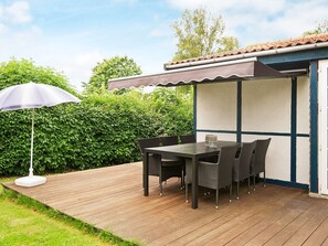 An outdoor patio with a table and chairs, a covered seating area, and a white umbrella. - 4 Person Holiday Home in Hejls (Hejls)