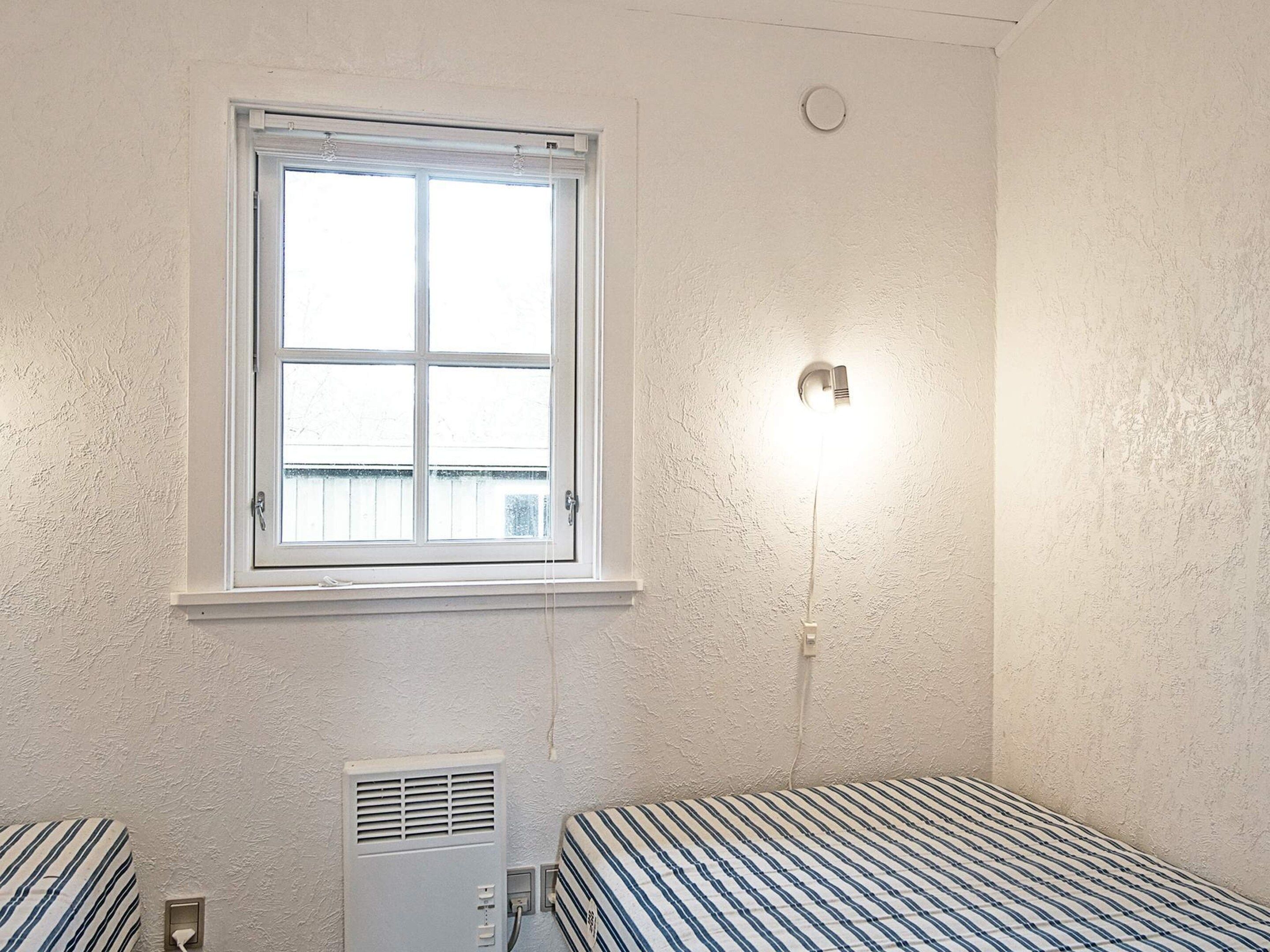 Une pièce avec une fenêtre, un luminaire fixé au mur et un radiateur.