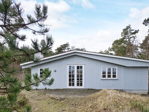 Une maison de plain-pied avec un toit à pignon, deux fenêtres et une porte dotée d’un panneau de verre.