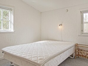 Une chambre avec un lit simple, une lampe fixée au mur et une fenêtre.