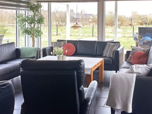 Un salon moderne avec un canapé en cuir noir, une table basse en bois et une plante en pot.