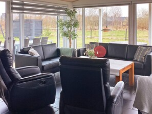 A sunroom with a sofa, chairs, a table, and a view of the outdoors.