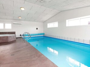 Une piscine intérieure dotée d’un plafond transparent, d’un banc intégré et d’une fenêtre laissant entrer la lumière naturelle.