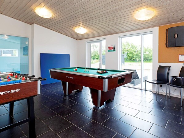 A billiards room with a pool table and a foosball table.
