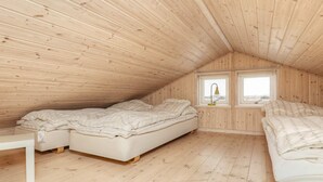 Un dormitorio en áticos pequeño con dos camas, una ventana y paredes de madera.