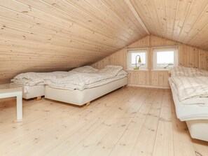A small attic bedroom with two beds, a window, and wooden walls. - 5 Star Holiday Home in Vaeggerlose (Vaeggerlose)