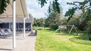 A patio area with outdoor seating and a play structure. - 5 Star Holiday Home in Blavand (Blavand)