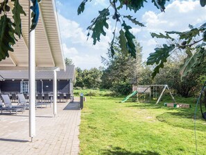 A patio area with outdoor seating and a play structure. - 5 Star Holiday Home in Blavand (Blavand)