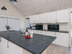 A modern kitchen with white cabinets, a black countertop, and stainless steel appliances. - 5 Star Holiday Home in Blavand (Blavand)