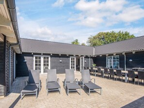 A building with a tiled roof and a patio area with outdoor seating. - 5 Star Holiday Home in Blavand (Blavand)