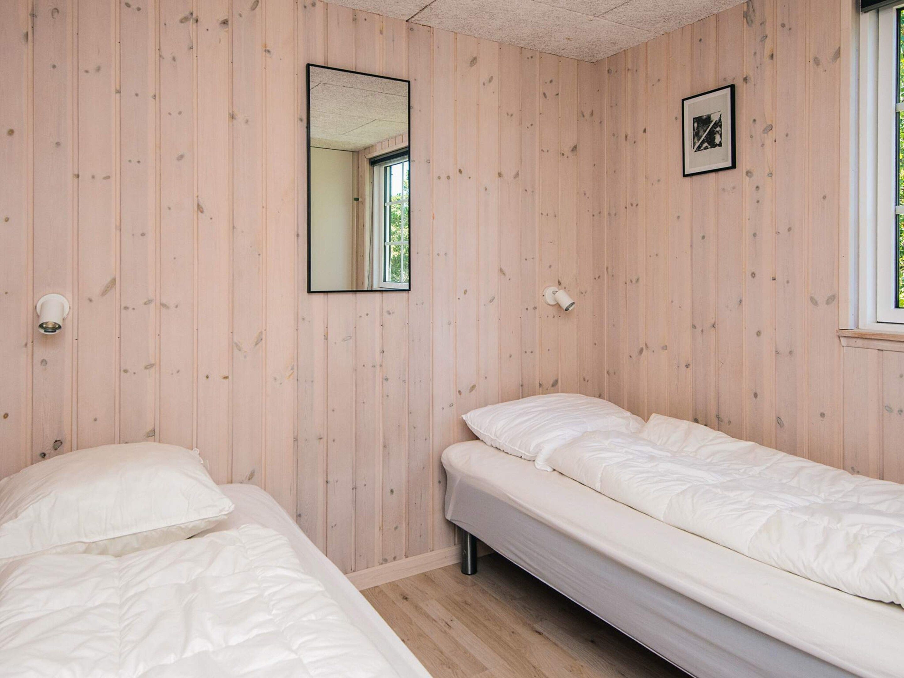 Een kamer met twee bedden, een spiegel, een ingelijst kunstwerk en een raam.