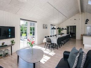 A spacious living area with a dining table, sofas, a TV, and a kitchen area. - 5 Star Holiday Home in Blavand (Blavand)