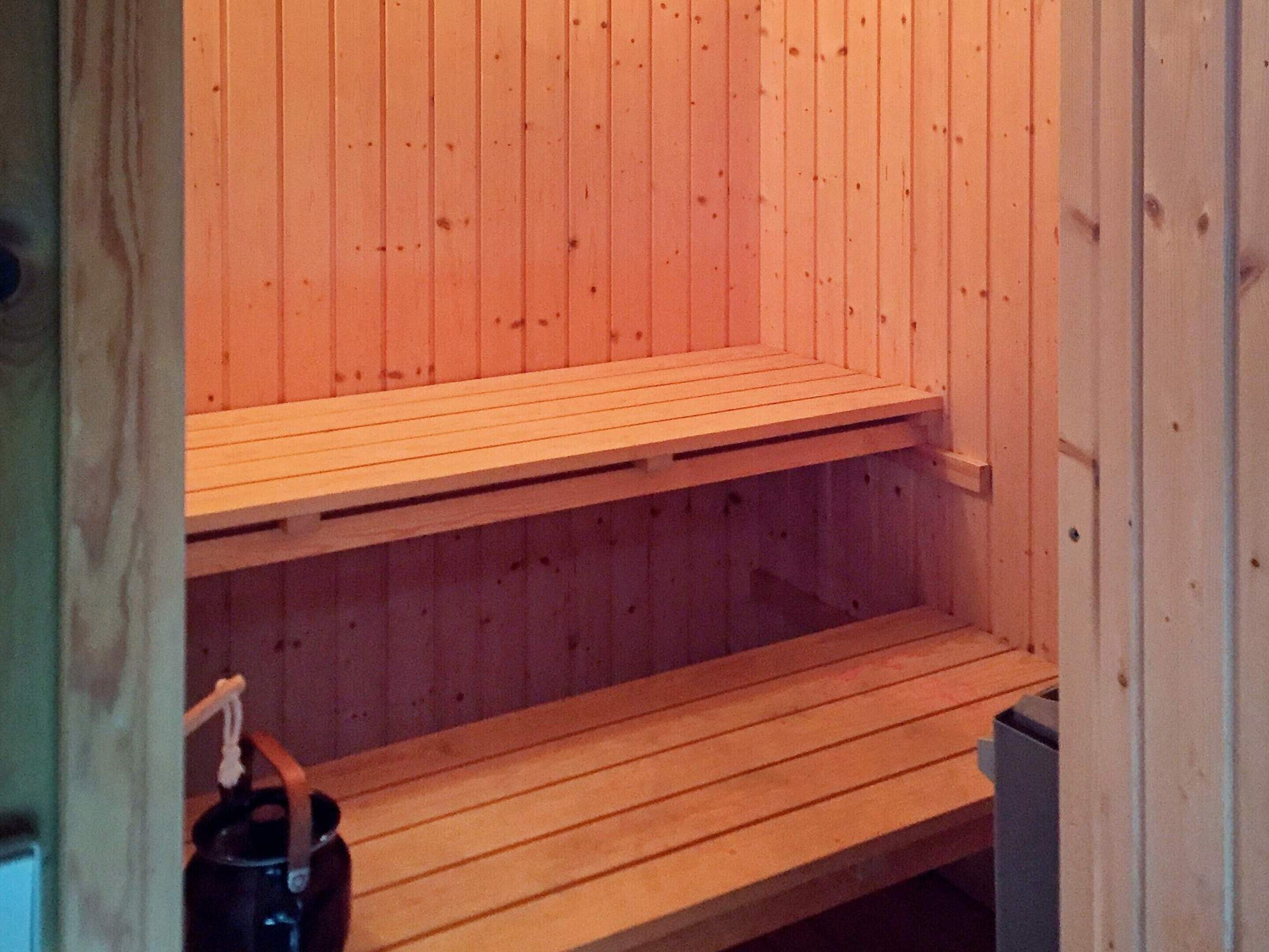 Een sauna met houten banken en een metalen bak.