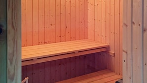 Eine Sauna mit Holzbänken und einem Metallbecken.