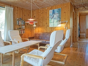 A wooden interior with a sofa, chairs, a table, and a bookshelf. - Cozy Holiday Home in Bornholm near Sea (Nexø)