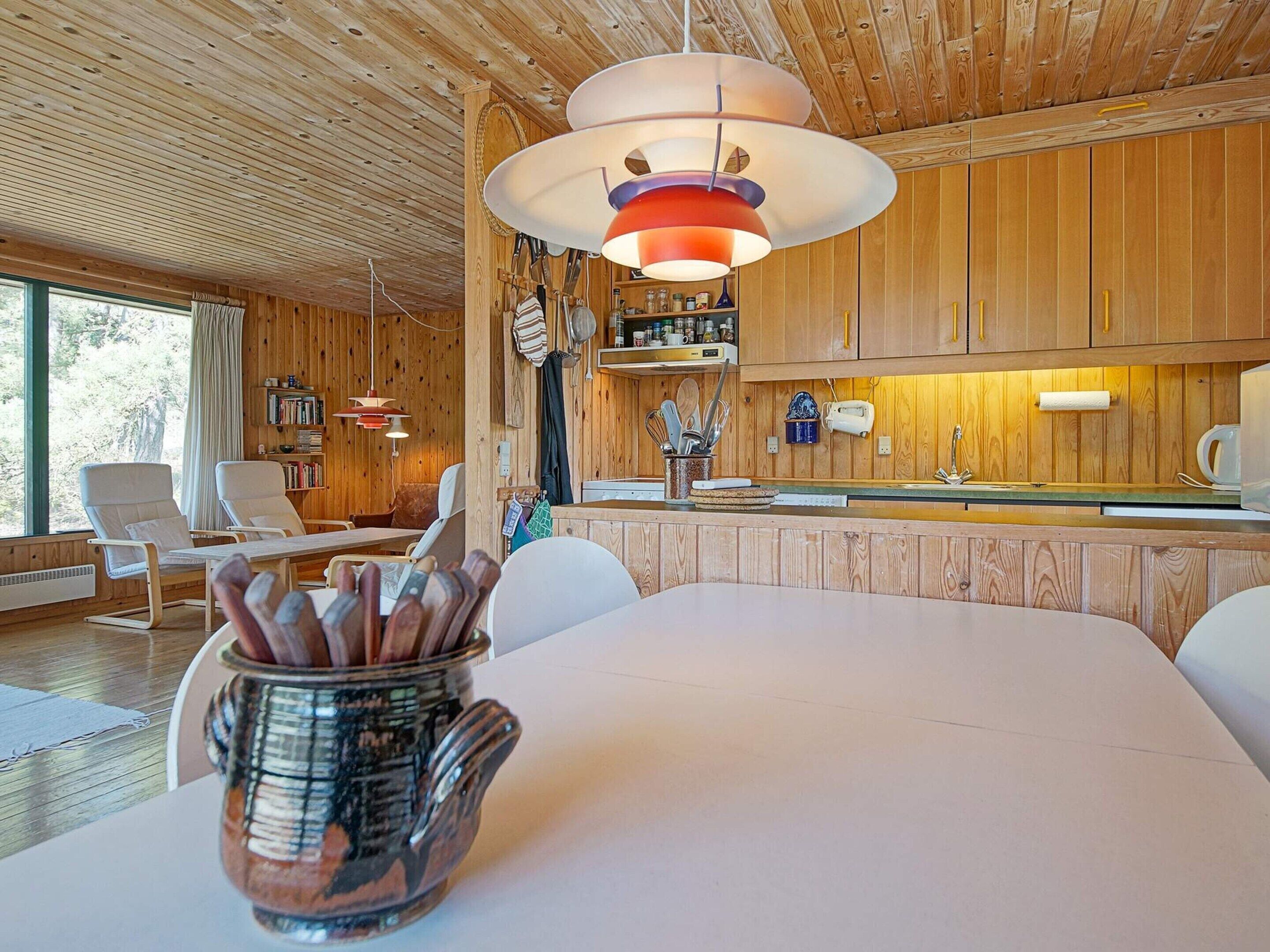 Una cocina moderna con armarios de madera, un comedor con mesa blanca y un amplio ventanal.